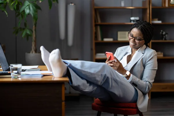 Jeune femme d'affaires africaine détendue accro au téléphone retardant sur le lieu de travail — Photo