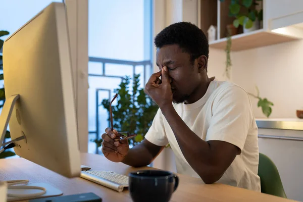 Уставший парень удаленный веб-разработчик снять очки чувствовать напряжение глаз после сверхурочной работы компьютера дома — стоковое фото