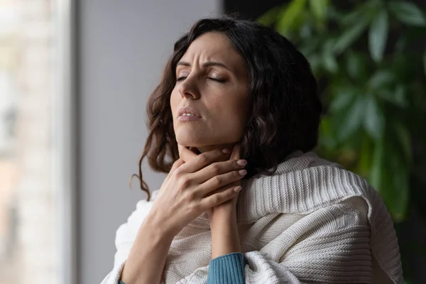 Ideges beteg nő, aki otthon áll, megérinti a nyaki mirigyek duzzanatát, és fáj a torka a vírustól — Stock Fotó