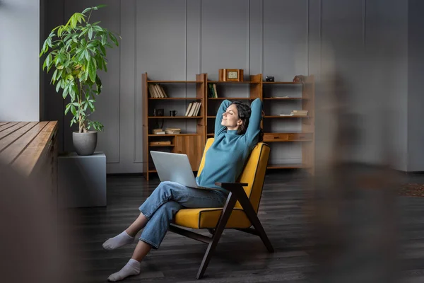 Happy uśmiechnięta kobieta freelancer z laptopem na kolanach relaks w biurze domu z rękami za głową — Zdjęcie stockowe