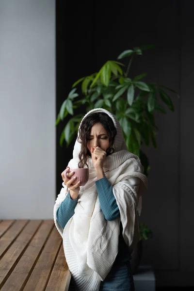 Ekoseye sarılı sağlıksız bir kadın sıcak bir fincan çay ve öksürük tutuyor, boğazında ağrı hissediyor. — Stok fotoğraf