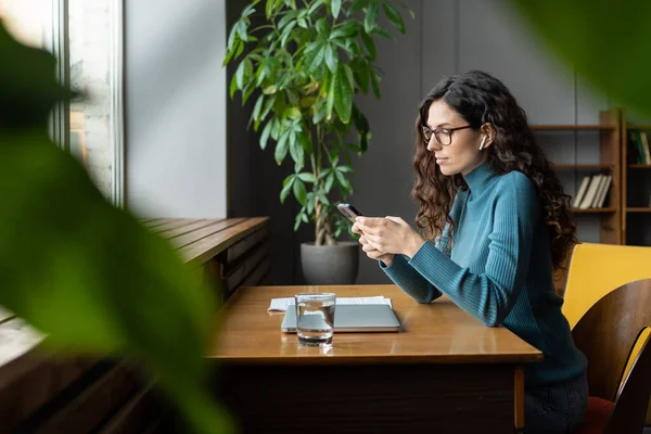 Kobieta copywriter freelancer za pomocą smartfona do sprawdzania mediów społecznościowych w miejscu pracy zdalnie — Zdjęcie stockowe