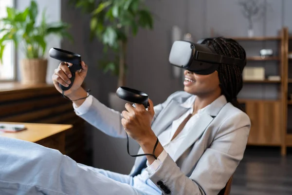兴奋的非洲女人戴着Vr眼镜，带着虚拟实境耳机的操纵杆体验 — 图库照片