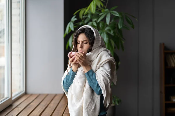 Ongezonde vrouw met gezwollen lymfeklieren of zere keel gewikkeld in plaid drinken van hete thee thuis — Stockfoto
