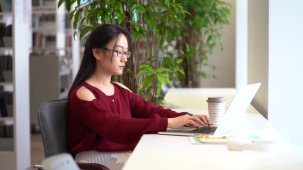 深刻な学生の女の子は、大学図書館での遠隔教育のための試験使用ラップトップコンピュータの準備 — ストック動画