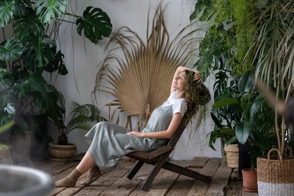 Удовлетворенная спокойная женщина флорист расслабляющий в закрытом саду насладиться психического баланса и благополучия дома — стоковое фото