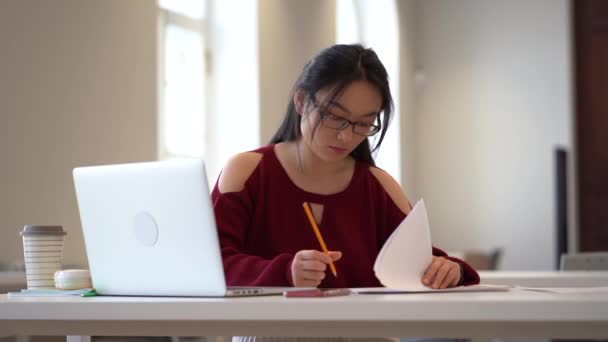 Fiatal ázsiai lány ül íróasztal osztály tér tanulmány laptop írás notebook felkészülés vizsgára — Stock videók