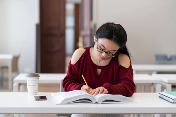Slim aziatisch meisje schrijven schets tijdens de voorbereiding voor examen in de leeszaal of klas — Stockfoto