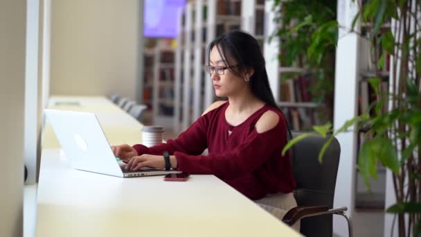 진지 한 여학생 이 대학 도서관에서 원격 교육을 위해 노트북 컴퓨터를 사용 한다. — 비디오