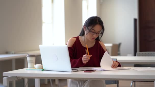 Koncentrált ázsiai női hallgató készül vizsga vagy csinál házi feladatot az egyetemi olvasóteremben — Stock videók