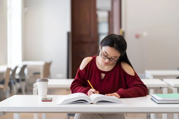 Jong meisje student studie klaslokaal maken beoordelingen van boek voor te bereiden op examen in de universiteit — Stockfoto