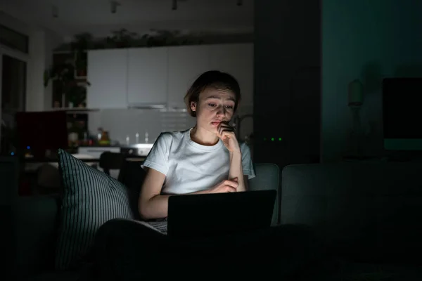 Anxious woman in bed using laptop at night, can not stop scrolling news media before bedtime.