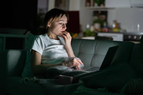 Nervózní žena v posteli pomocí notebooku v noci, nemůže přestat posouvat zprávy média před spaním. — Stock fotografie