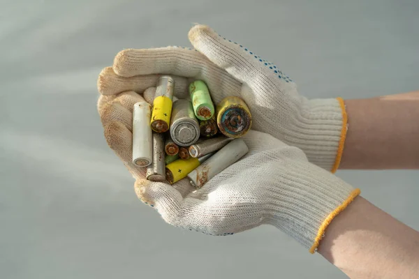 Primer plano de las manos femeninas en guantes de protección de algodón que sostienen pilas alcalinas usadas montón — Foto de Stock