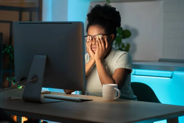 Перегруженная работой африканская женщина-фрилансер чувствует напряжение глаз и усталость во время длительного использования компьютера — стоковое фото