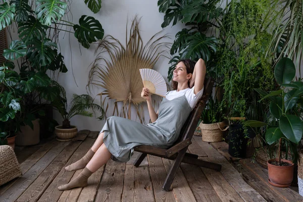 Alleviamento dello stress dopo il lavoro. Rilassato ragazza trascorrere del tempo in accogliente giardino interno con pianta monstera — Foto Stock