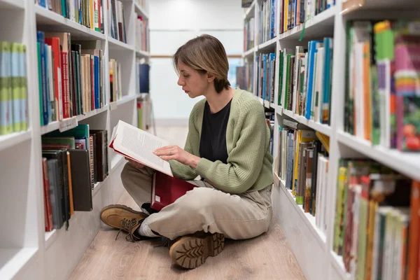 Enthousiaste Vrouw Van Middelbare Leeftijd Zit Vloer Gekruist Tussen Boekenplanken — Stockfoto