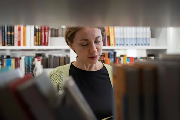 Kvinnlig Mogen Student Står Mellan Bokhyllor Universitetsbiblioteket Plockar Upp Bok — Stockfoto