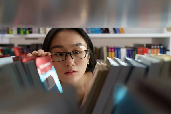 教育研究のために大学や大学図書館の本棚から本を選ぶ女子学生 アジアの少女読者は書店で小説を探している 奨学金と教育機会の概念 — ストック写真