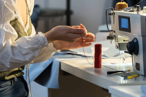 女裁缝拿着线轴在缝纫机上缝衣服 车间的专业女裁缝工作创造了新产品 工作室的自谋职业工作室业主 小商业 — 图库照片