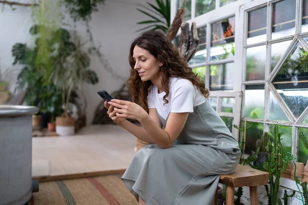 Glücklich Lächelnde Millennial Floristin Entspannen Gewächshaus Mädchen Halten Smartphone Sms — Stockfoto