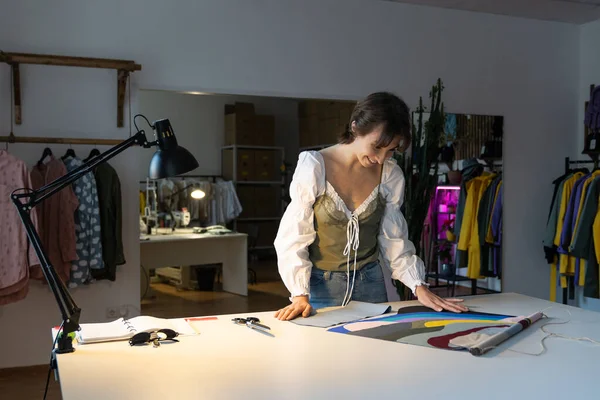 Creative woman dressmaker work on new clothes collection in studio choose fabric material at workplace. Female designer looking at textile sample in workshop. Tailor entrepreneurship, small business