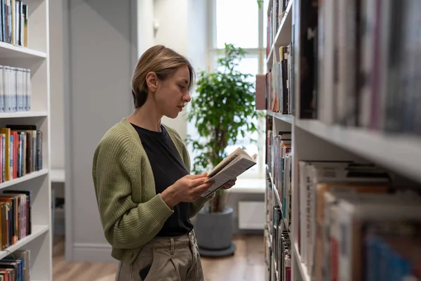 Задумчивая Женщина Средних Лет Стоит Между Рядами Книжных Полок Поисках — стоковое фото