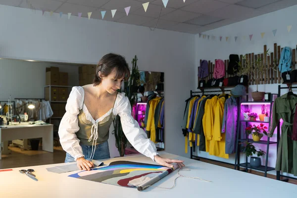 Woman dressmaker work late in studio choosing fabric samples for new clothes collection sewing. Female designer stay in workshop late busy with brand and small business development. Atelier ownership