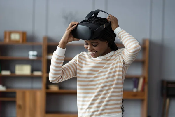 受到启发的非洲女孩在家里客厅戴上Vr头盔 享受虚拟现实网络游戏世界的模拟 快乐的女人喜欢用新的电子设备娱乐 — 图库照片