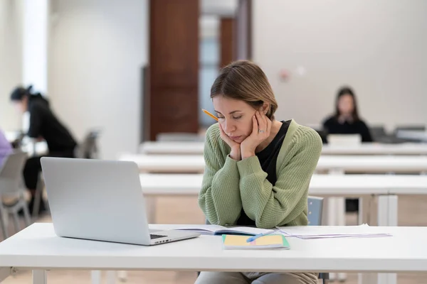 Sad mature female student feeling tired and unmotivated while studying online on laptop computer in classroom, middle-aged 45s woman preparing for exams, taking second higher education in middle age