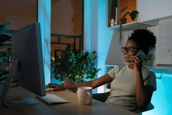 Positive African American Woman Glasses Using Computer Mouse Talking Smartphone — Fotografia de Stock