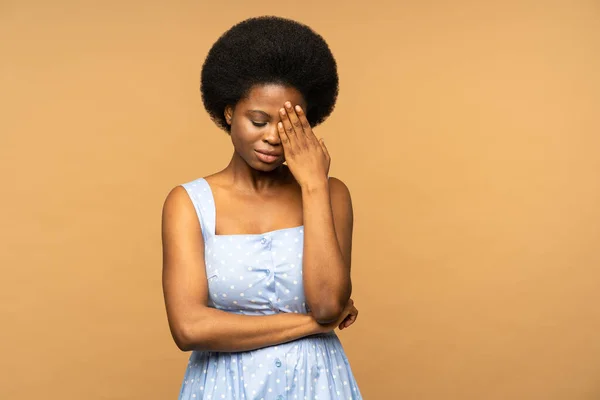 Shocked african american woman cover face with hand after bad news crying received bad e-mail having big problems notification from bank isolated on beige background. Black girl in panic feels unhappy