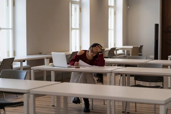 アジアの学生の女の子は 図書館でオンラインで勉強しながら 大学の教室でラップトップで机に座って学習教材を読み 疲れて 集中して学習に集中しようとしています — ストック写真