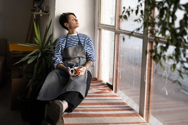 Young Creative Artisan Crafts Woman Wearing Apron Drinking Morning Coffee — Stok fotoğraf