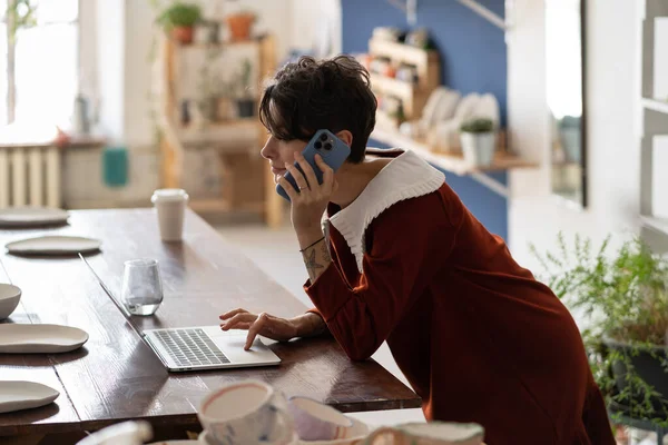 Молода Жінка Власник Гончарного Бізнесу Використовує Ноутбук Розмовляє Клієнтом Телефону — стокове фото