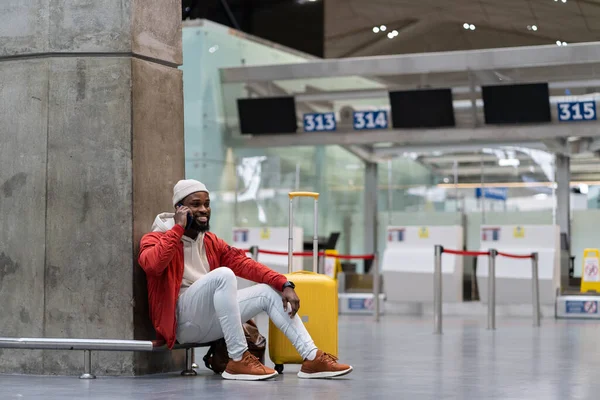 Радісний Усміхнений Афроамериканець Відпочиває Сучасному Аеропорту Жовтою Валізою Очікуючи Оголошення — стокове фото