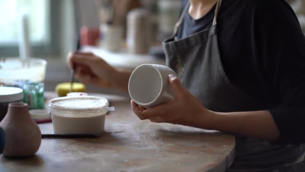 Молодая Женщина Черном Фартуке Любит Рисовать Посуду Ручной Работы Сидя — стоковое видео