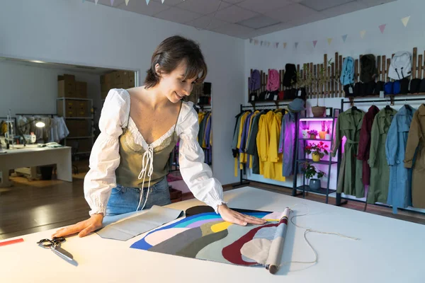 Woman dressmaker work late in studio choosing fabric samples for new clothes collection sewing. Female designer stay in workshop late busy with brand and small business development. Atelier ownership