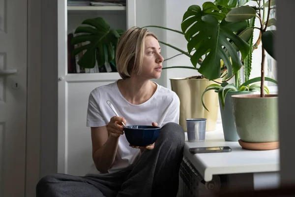 Thoughtful Mature Woman Sits Windowsill Eating Healthy Breakfast Alone Shabby — Photo