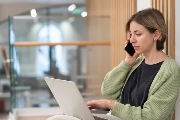 Serious Woman Holding Smartphone Discussing Project Details While Working Online — Photo