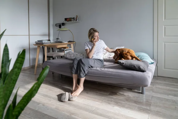 Mature Woman Talks Phone Strokes Favourite Vizsla Dog Lying Bed — Stock Photo, Image