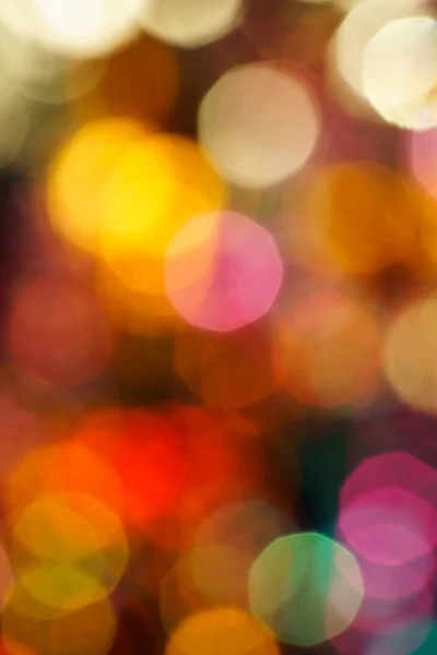 City lights at night in background with colorful lights, blurred focus. Festive abstract defocused colored neon light background with circular bokeh, closeup.