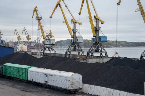 Loading coal anthracite into the railway freight wagons in port with crane bucket, industrial background.
