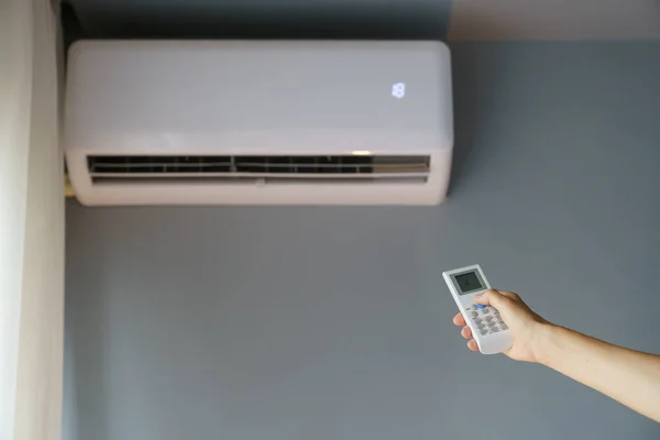 Owner Uses Remote Control Turn Air Conditioner Hanging Grey Wall — Stock Photo, Image