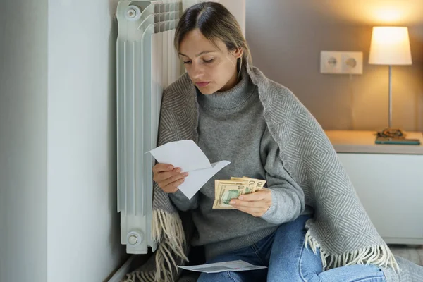 Droevige Vrouw Leunend Koude Centrale Verwarming Radiator Kijkt Naar Rekeningen — Stockfoto