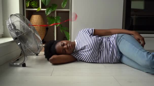 Calmo Jovem Africano Deitado Chão Frente Ventilador Elétrico Trabalhando Dia — Vídeo de Stock