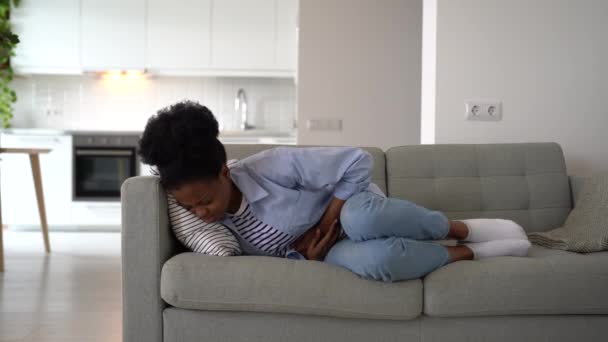 Εξαντλημένη Αφρο Αμερικανίδα Ξαπλωμένη Στον Καναπέ Αρπάζοντας Την Κοιλιά Βιώνοντας — Αρχείο Βίντεο