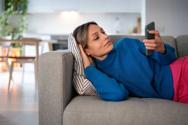 Avslappnad Kvinna Läser Blogg Eller Forum Telefon Ligger Soffan Vardagsrummet — Stockfoto