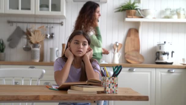 不幸な10代の少女は母親に電話で父親と話すのを聞いて悲しい台所のテーブルに座っている 白人女性は学校の先生や校長に何かを呼び出すことを議論緊張しています — ストック動画
