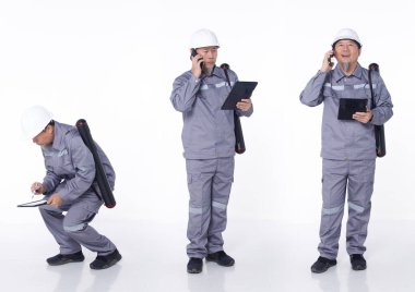 50 'lerin tam boy portresi. 60' ların Asyalı, gri üniformalı yaşlı adam. Elektrik mühendisi, izole edilmiş. Elektrik teknisyeni erkek dijital tablet çizelgesi taşır kontrol listesi notu, beyaz arka plan stüdyosu